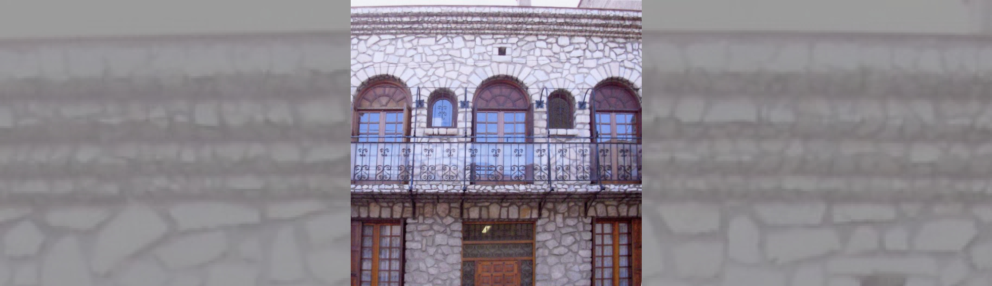 Facade en pierre ,les baies sont en  arc de plei cintre et le garde corps en fer forgé 