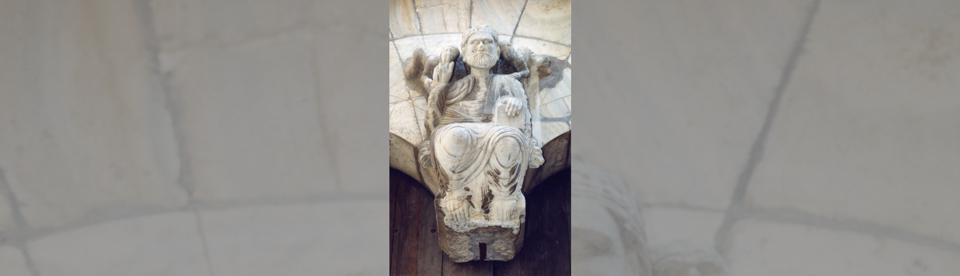 Dessus de portail sculpté: le Christe en majesté avec un ange sur chaque épaule semblant lui parler à l'oreille.